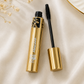 HSA luxury gold mascara tube open with black volumising wand applicator on cream satin fabric with dried flowers